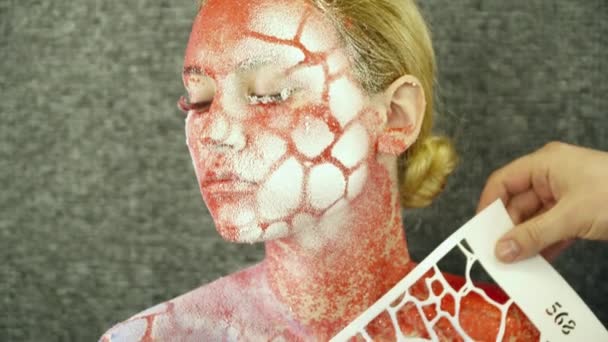 Creating body art on young womans face with the help of a stencil — Stock Video