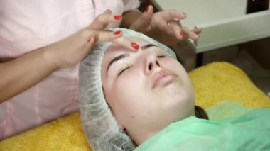 Güzellik uzmanı salonda genç bir kadın için microblading yordam yapıyor