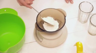 Kadının ekleyerek unu tencereye eller.