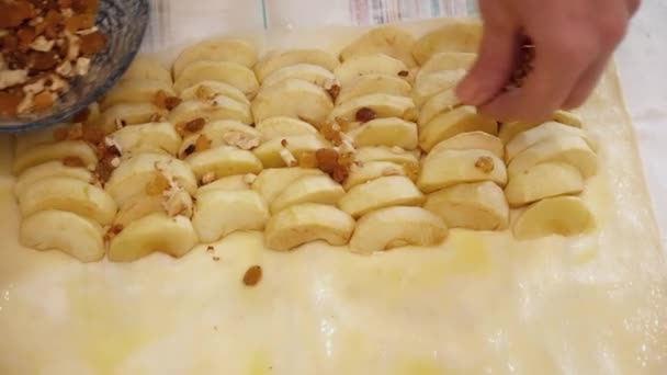 Womans hands adding nuts to the apples on the dough — Stock Video