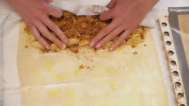 Manos de mujer enrollando la masa con manzanas y nueces para hacer strudel — Vídeo de stock