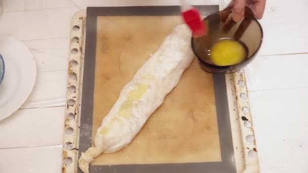 Womans hands covering raw strudel with the stirred eggs — Stock Video