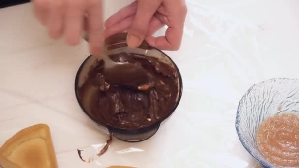 Dames handen de chokolate roeren in de kom met de lepel — Stockvideo