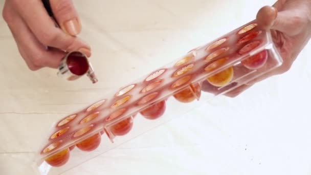 Le mani delle donne spruzzano il colore arancione alle forme di caramella — Video Stock