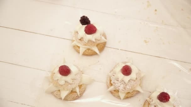 Mujer está decorando la eclair con bayas en la mesa de madera — Vídeos de Stock