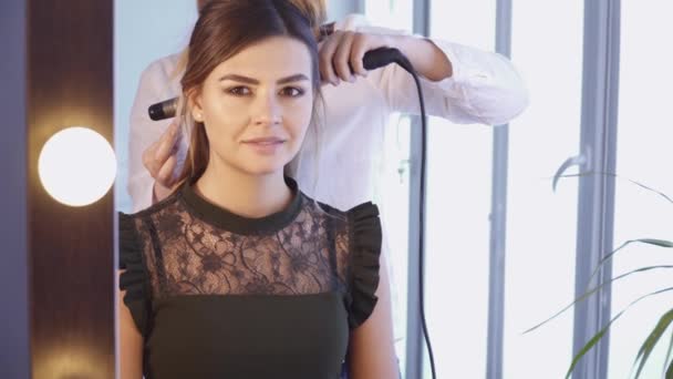 Penata rambut menciptakan gaya rambut untuk seorang wanita muda — Stok Video