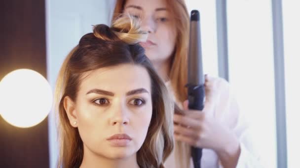 Hairdresser creating a hairstyle for a woman in salon — Stock Video