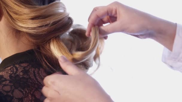Стиліст волосся створює зачіску для молодої жінки — стокове відео