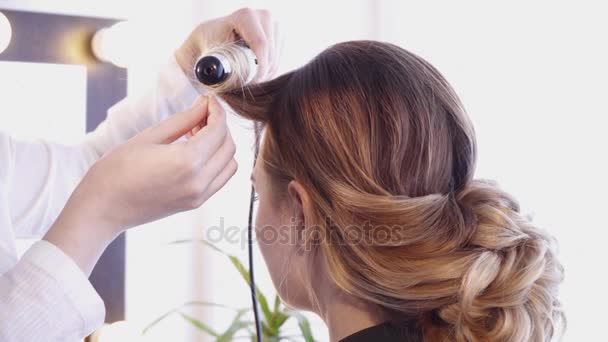 Peluquería creando un peinado para una mujer morena en peluquería — Vídeo de stock