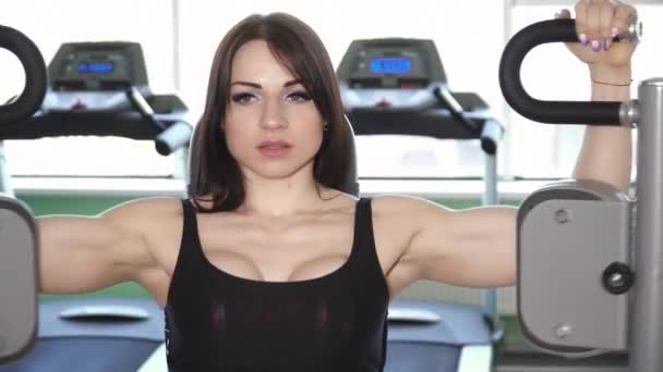 Mujer joven entrenando en la máquina de cubierta de pec en el primer plano del gimnasio — Vídeos de Stock