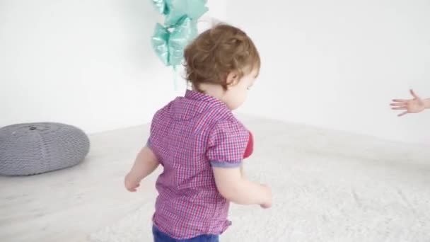 Маленький хлопчик біжить до мами, вона бере його до рук повільний рух — стокове відео