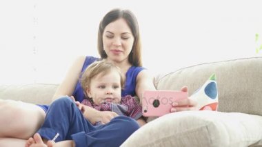 Genç anne oğlu Divan ile Smartphone çizgi film izlerken