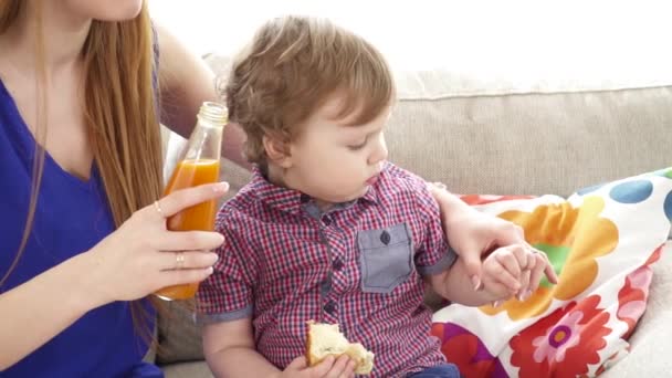 Jovem mãe bonita alimentando seu pequeno filho câmera lenta — Vídeo de Stock