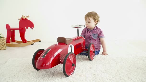 Niño pequeño jugando con un coche de juguete grande — Vídeos de Stock