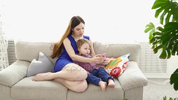 Joven madre viendo dibujos animados en el teléfono inteligente con su hijo — Vídeos de Stock