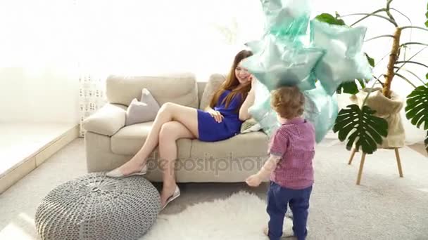 Malý syn hraje s balónky, zatímco jeho matka mluví o telefonu — Stock video