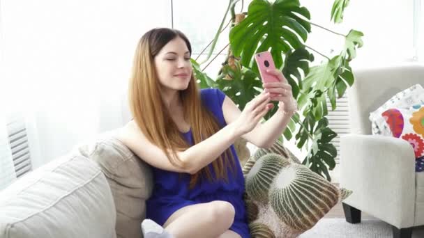 Молода жінка робить селфі в кімнаті — стокове відео