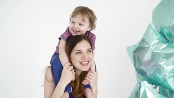 Schöne Mutter hält ihr Baby auf ihren Schultern in der Nähe der Ballons Nahaufnahme — Stockvideo