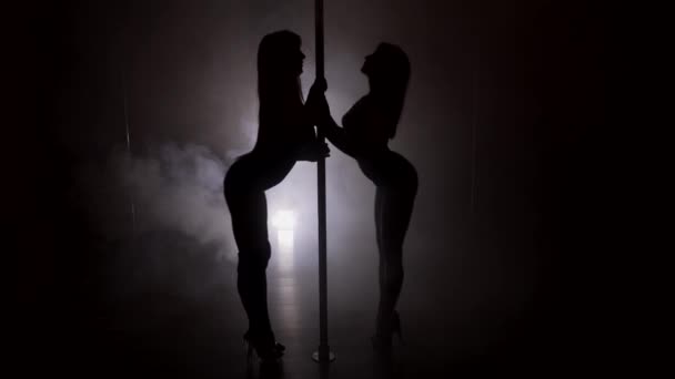 Siluety dvou žen, tanec na tyči