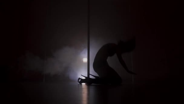 Silhouette of a young woman dancing near the pole in strip shoes — Stock Video
