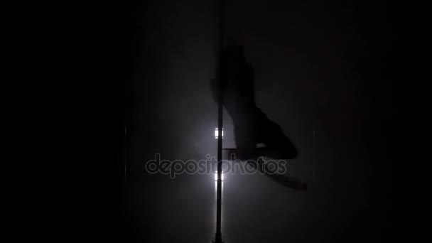 Muda langsing siluet dalam rok menari dekat tiang di ruang gelap — Stok Video
