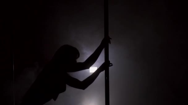 Sziluettjét egy táncoló fiatal nő a pole füst lassítva — Stock videók