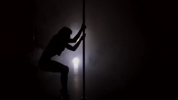 Sziluettjét a táncoló fiatal nő a pole a sötét szobában lassítva — Stock videók