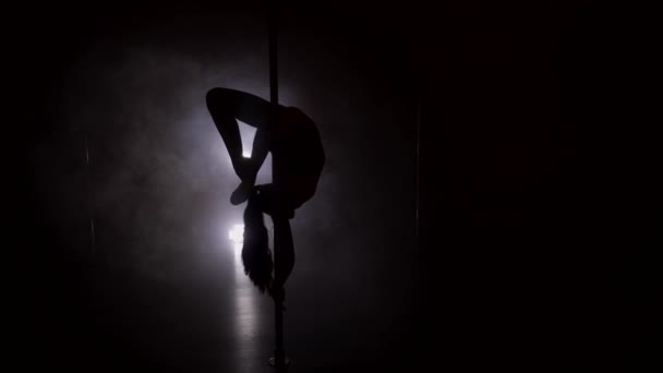 Silhouette einer schlanken Frau, die kopfüber auf der Stange tanzt — Stockvideo