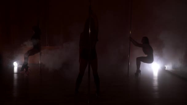 Silueta tří štíhlé ženy tančí poblíž pólu v kouři — Stock video