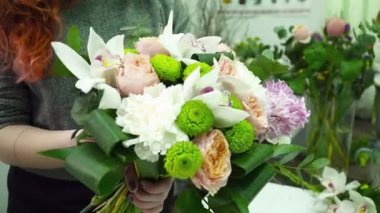 Çiçekçi kadın orkide ve gül closeup ile güzel bir buket yapma