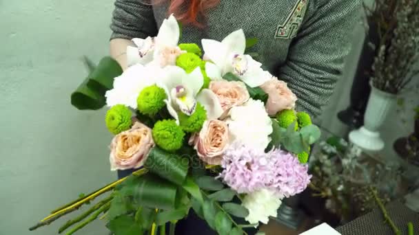Ανθοπωλείο γυναίκα κάνοντας μια όμορφη ανθοδέσμη με τριαντάφυλλα και ορχιδέες — Αρχείο Βίντεο