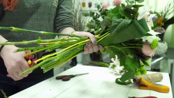 Цветочница делает красивый букет в магазине крупным планом — стоковое видео