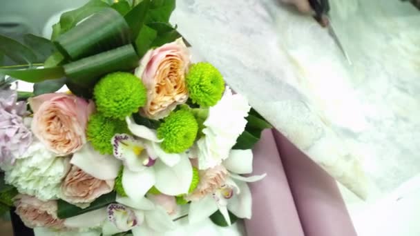 Floristería envolviendo un hermoso ramo con papel para la decoración en las tiendas florales — Vídeos de Stock