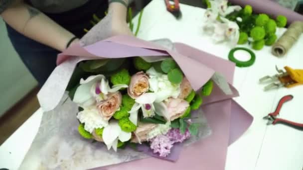 Fleuriste enveloppant un bouquet avec du papier pour la décoration dans la boutique — Video