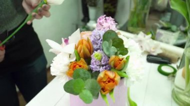 Ahşap masa üstünde belgili tanımlık kutu içinde güzel bir buket oluşturma çiçekçi