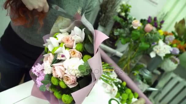 Florista que envolve um buquê com papel para decoração em loja de flores — Vídeo de Stock