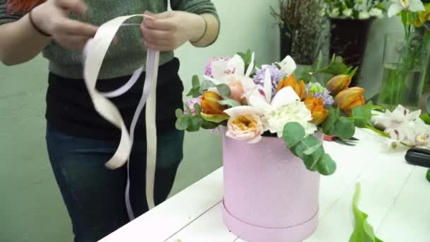Florista criando um buquê na caixa com fita — Vídeo de Stock