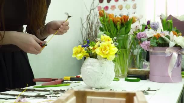 Флорист делает букет с желтыми цветами в белом котелке в магазине — стоковое видео
