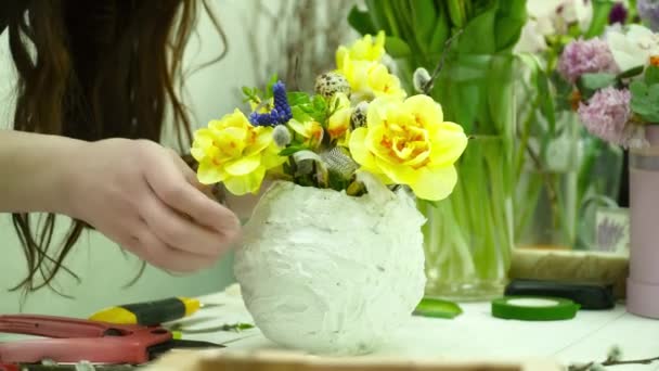 Florista fazendo um buquê com flores amarelas no pote de gesso branco na mesa closeup — Vídeo de Stock