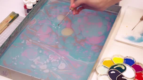 Un artista arrojando pintura al agua creando una imagen de ebru — Vídeos de Stock