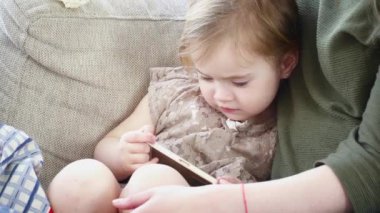 Genç anne kızı kanepede döşenmesi cellphone içinde oynamaktan