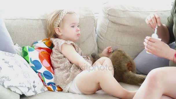 Giovane madre che nutre la sua bella figlia sul divano — Video Stock