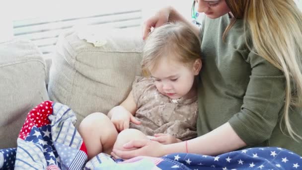 Mãe brincando no celular com sua filha deitada no sofá — Vídeo de Stock