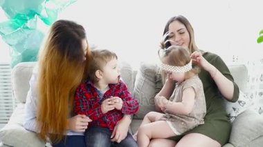 İki anne, çocukları ile kanepede oturan