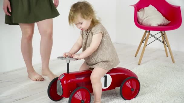 Μικρό κοριτσάκι παίζει με το αυτοκίνητο παιχνίδι στο δωμάτιο — Αρχείο Βίντεο