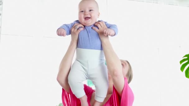 Bonita mãe brincando com seu filho de 6 meses jogando-o em câmera lenta — Vídeo de Stock