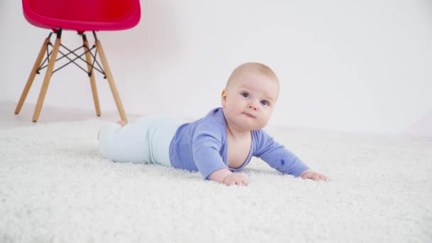 Bastante pequeño niño de 6 meses acostado en la alfombra — Vídeo de stock