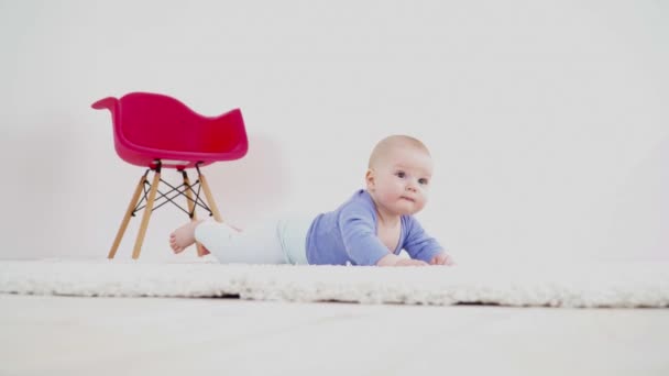 Pretty cute baby boy of 6 months laying on the carpet — Stock Video