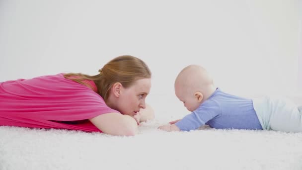 Young mother laying on the carpet with her son of 6 months old closeup — Stock Video