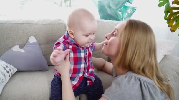 Jonge moeder met haar 6 maanden oude zoon spelen terwijl hij op de bank zit — Stockvideo